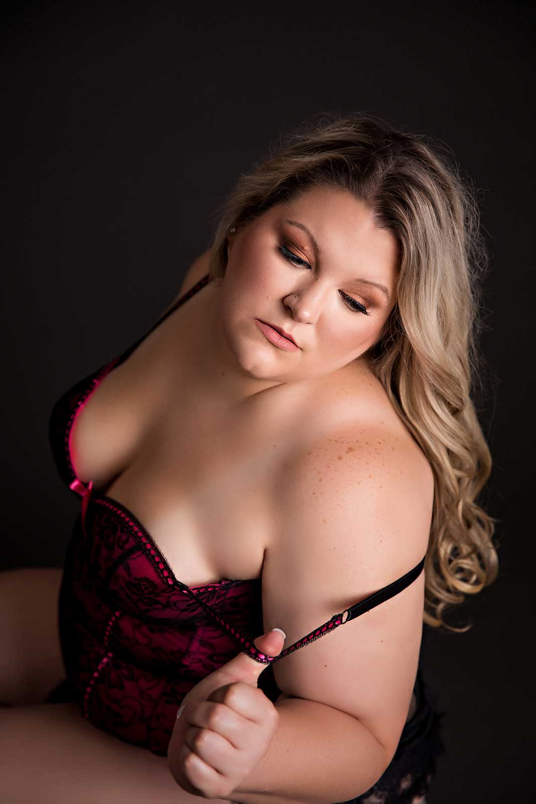 Woman in corset on black background boudoir session